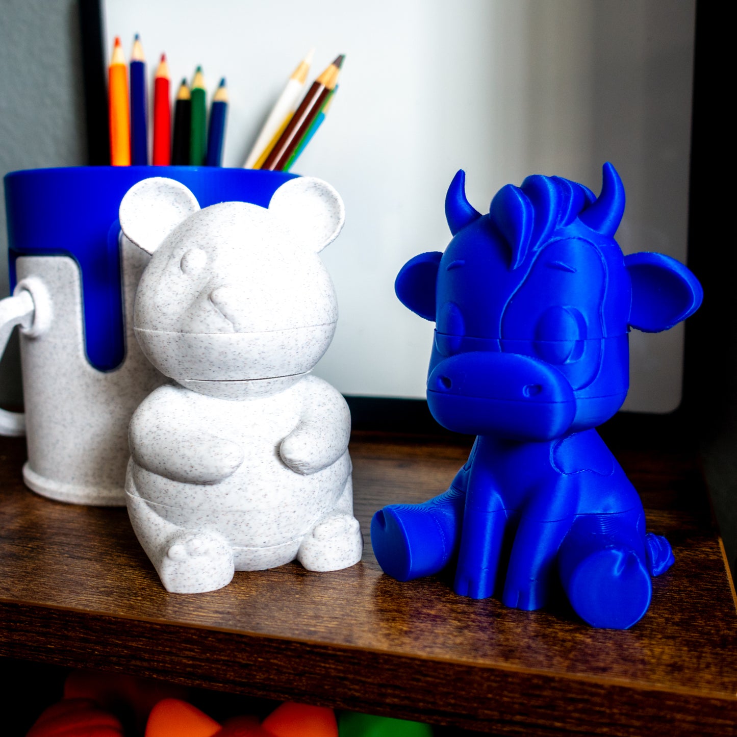 Mooch the cow and Munch the panda paired beside a paint can, illustrating desk-friendly size and collectible appeal