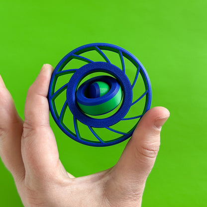 A blue and green fidget spinner with a gyro in the middle and blades like a fan on the outer circle being held by a hand