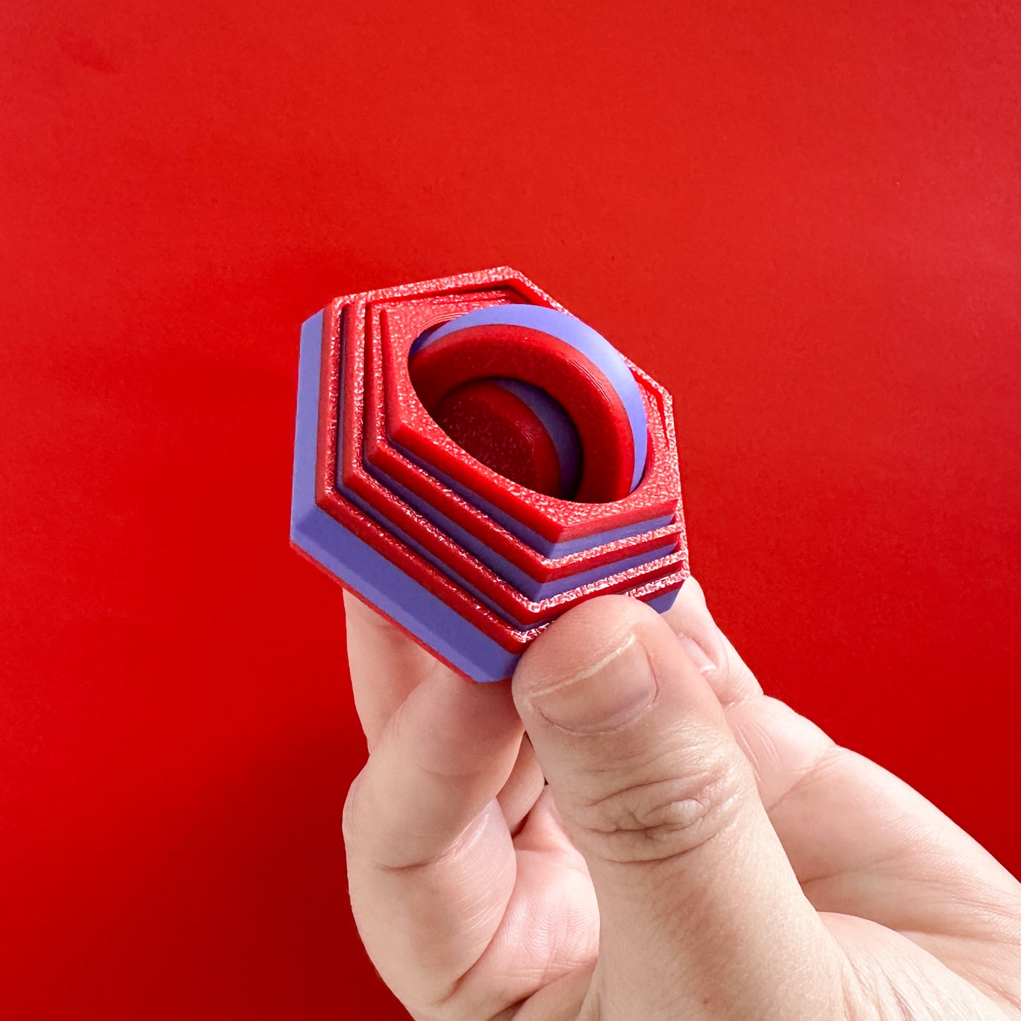 A small purple and red fidget toy with shifting sides and a gyro in the middle