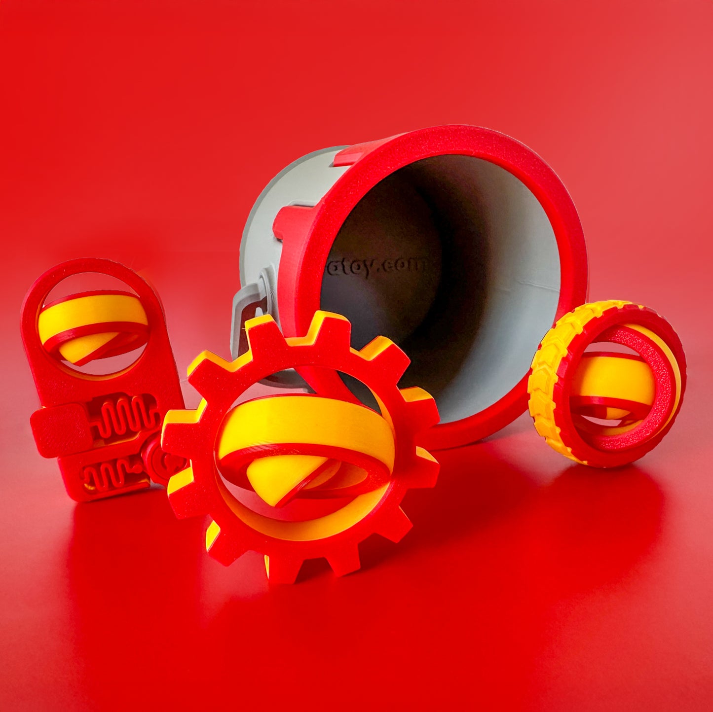 A set of three red and yellow fidget toys with a paint can container with red drip on a red backdrop