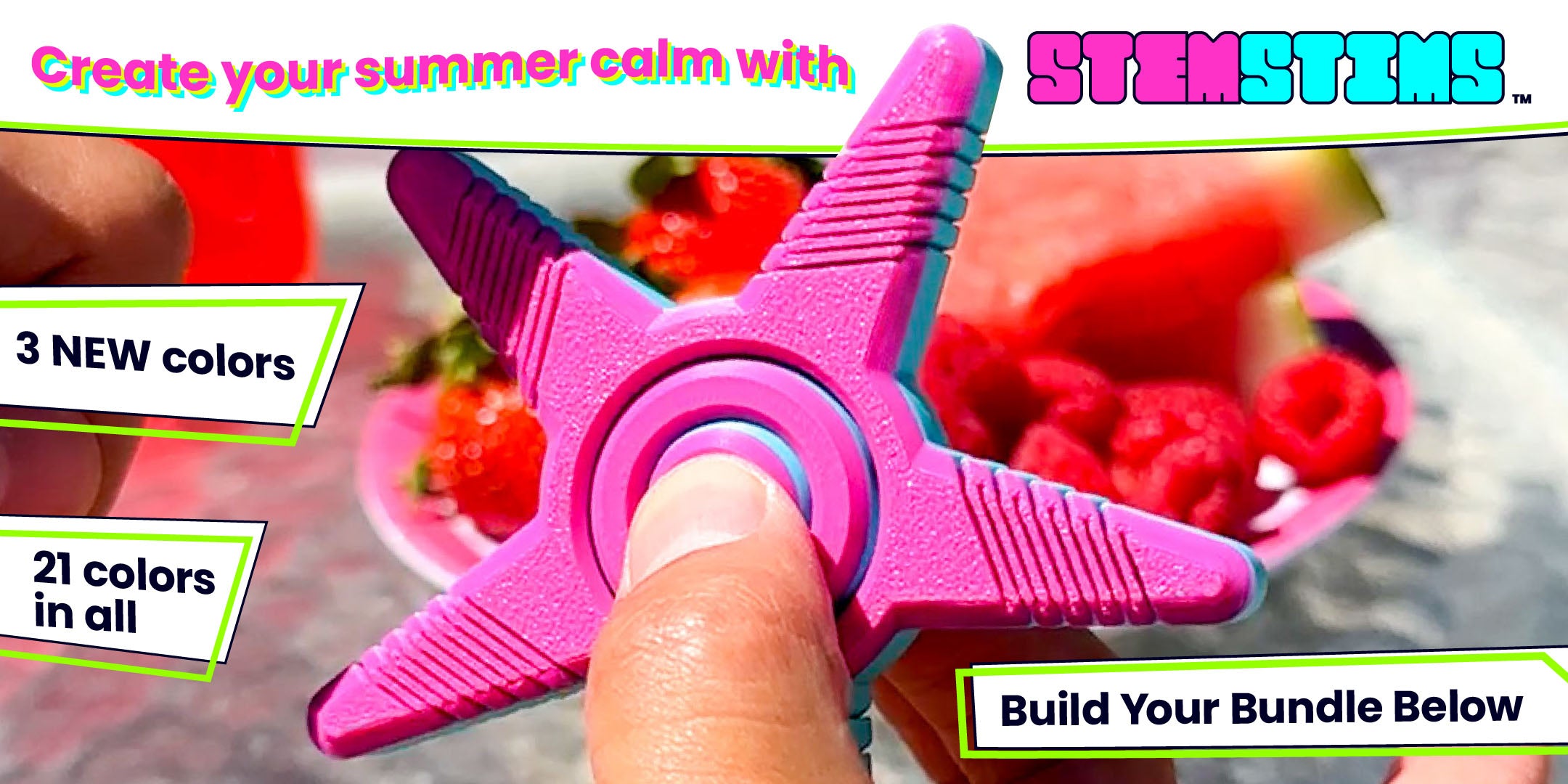 A magenta and aqua blue star shaped fidget spinner is being held by a hand in front of a red and pink plate of fruit outdoors.