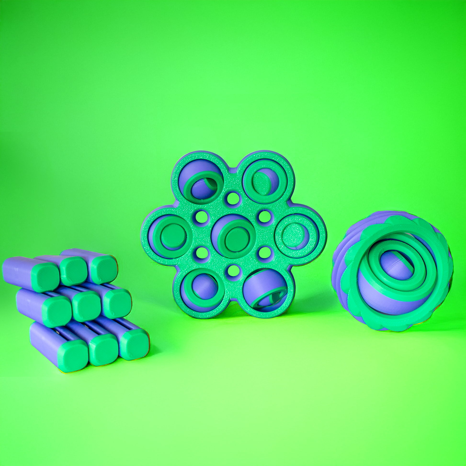 Three green and purple fidget toys on a green background.