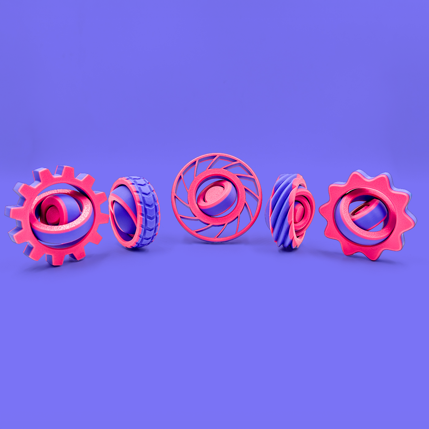 Pink and purple fidget spinners- 5 differently shaped toys on a purple background
