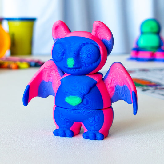 Swoosh Bat custom articulated animal toy posed on a coffee table, designed for tactile play and fidget-friendly movement