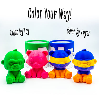 Two pairs of Roar the tiger and Rumble the gorilla paired beside a paint can, illustrating desk-friendly size and collectible appeal