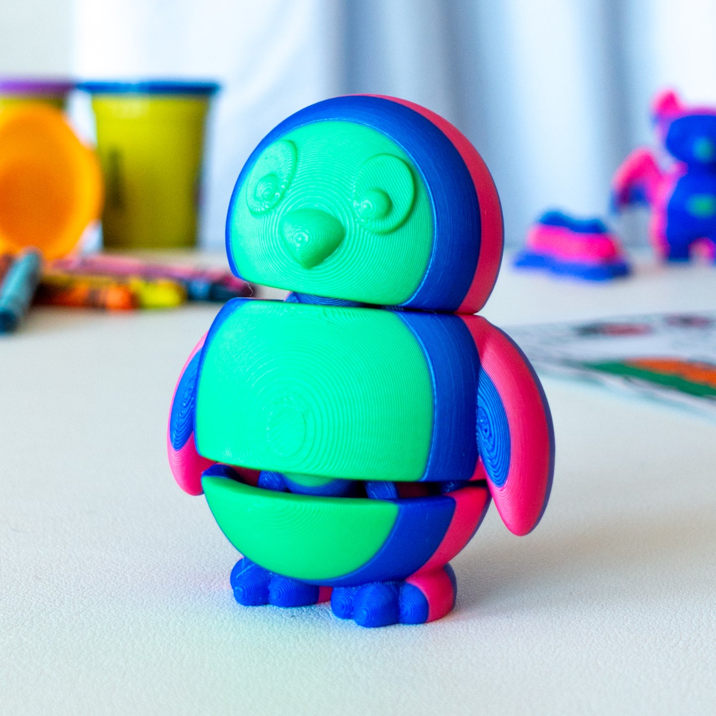 Tux Penguin custom articulated animal toy posed on a coffee table, designed for tactile play and fidget-friendly movement