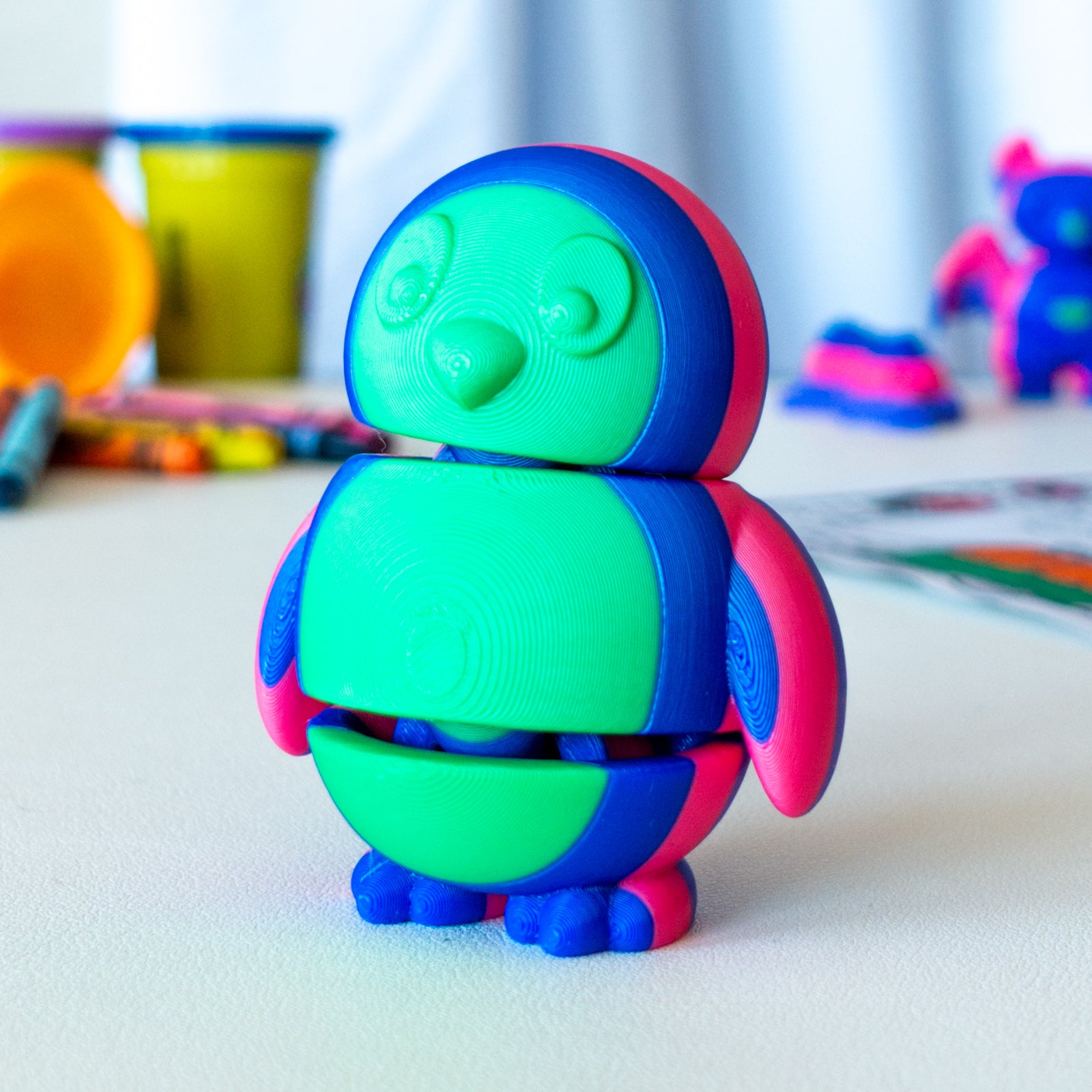 Tux Penguin custom articulated animal toy posed on a coffee table, designed for tactile play and fidget-friendly movement